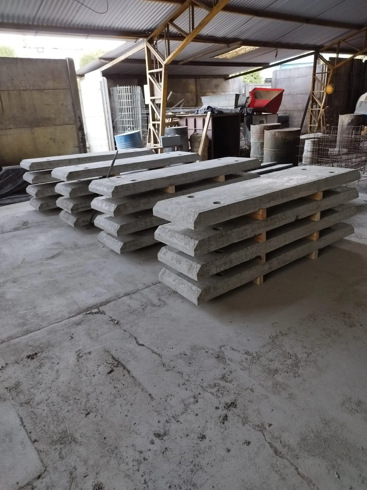 Pallets de losetas de hormigón recién fabricadas, apiladas bajo techo en la planta