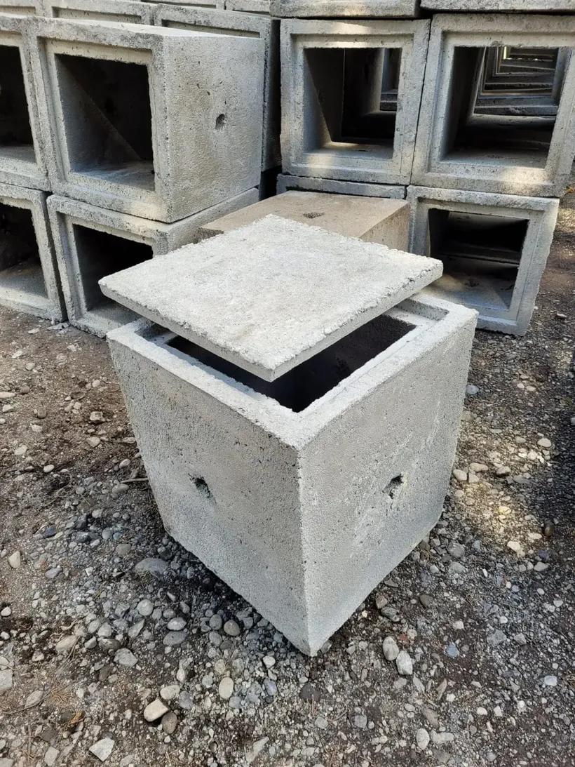 Cámara eléctrica de hormigón de 40 × 40 × 60 cm con su tapa, junto a una pila de cámaras en la planta de Vibrados Navarrete