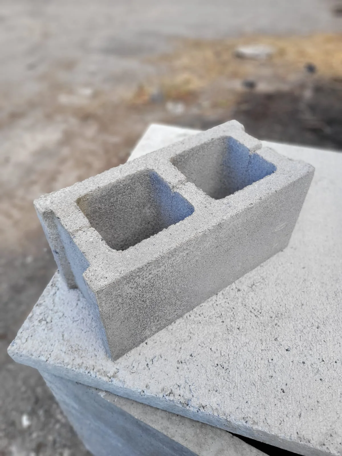 Detalle de un bloque hueco de hormigón vibrado fabricado por Vibrados Navarrete, apoyado sobre una placa de hormigón: se aprecian el árido, la textura de la superficie y los tabiques interiores de la pieza.